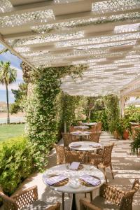 a patio with tables and chairs under a pergola at B bou Hotel La Viñuela & Spa in Viñuela