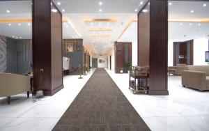 a lobby with a long hallway with tables and chairs at منازل بلقيس للشقق المخدومة in Hail