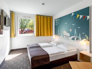 a bedroom with a bed and a window with yellow curtains at B&B Hotel Hamburg-Nord in Hamburg