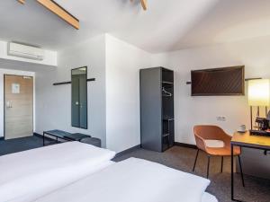 a room with a bed and a desk and a tv at B&B Hotel Hamburg-Nord in Hamburg