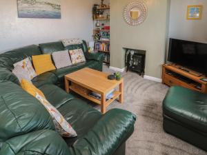 a living room with a green leather couch and a table at Island View Cottage in Morpeth