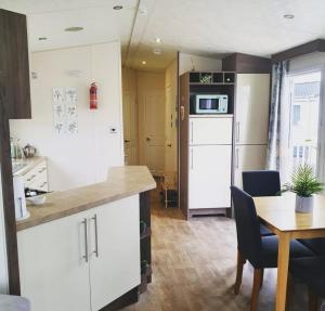 a kitchen and dining room with a table and a refrigerator at Kjs holiday home in Saint Osyth