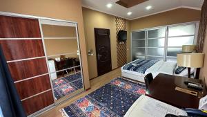 a bedroom with a bed and a desk and a mirror at Tian-Shan Hotel in Bishkek