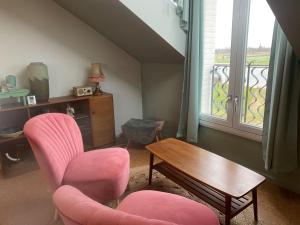 a living room with pink chairs and a table and a window at Het Veerhuis in Oeffelt