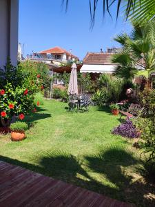 einen Garten mit einem Sonnenschirm, Stühlen und Blumen in der Unterkunft Maria's Paradise in Vónitsa