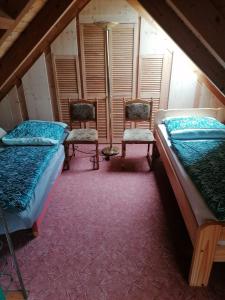 a attic room with two beds and two chairs at Ferien auf dem Land in Horka