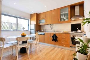 eine Küche mit Holzschränken und einem Tisch und Stühlen in der Unterkunft Townhouse Senhora da Rocha - Alporchinhos in Armação de Pêra