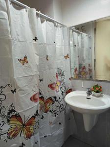 a bathroom with a sink and a shower curtain with butterflies at Sea Residences in Manila