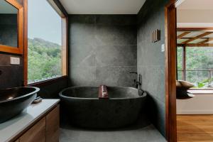 uma casa de banho preta com uma grande banheira e uma janela em Waterfall Lodge em Carool