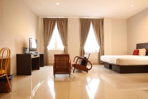a bedroom with a bed and a television and a chair at Bale Ocasa in Tangerang