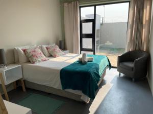 um quarto com uma cama, uma cadeira e uma janela em The Cabin em Swakopmund
