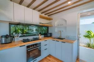 a kitchen with white cabinets and a fishtank at Villa Tiny - Romantic A-Shape 1BR Villa Close to Nyanyi Beach in Tanah Lot