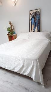 ein weißes Bett mit einer weißen Bettdecke darauf in der Unterkunft WhiteHome in Conegliano