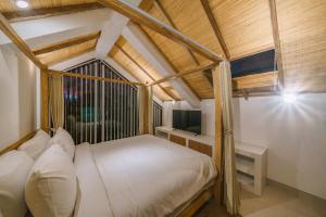 a bedroom with a white bed and a window at Villa Tiny - Romantic A-Shape 1BR Villa Close to Nyanyi Beach in Tanah Lot