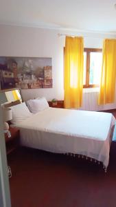 Schlafzimmer mit einem großen weißen Bett und gelben Vorhängen in der Unterkunft WhiteHome in Conegliano