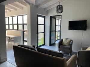 a living room with couches and a tv and a table at The Cabin in Swakopmund