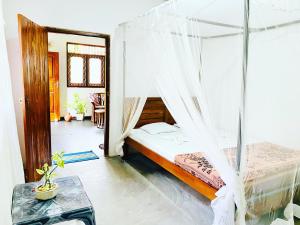 a bedroom with a bed with mosquito net at Surfing Waves Madiha in Matara