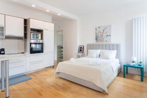 een witte slaapkamer met een bed en een keuken bij Flower Square Apartments in Zagreb
