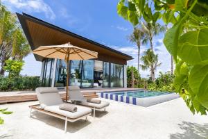 ein Haus mit einem Pool, 2 Stühlen und einem Sonnenschirm in der Unterkunft SO/ Maldives in Süd-Malé-Atoll