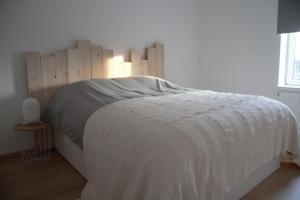 a bedroom with a white bed with a wooden headboard at Gîte du Lac Cosy in Fosses-La-Ville