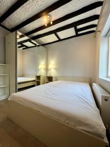 1 dormitorio con 1 cama blanca grande y espejo en The Windmill en Busheyheath