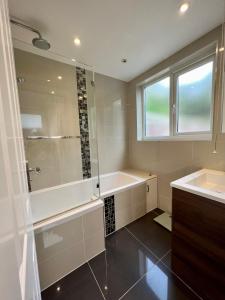 a bathroom with a shower and a tub and a sink at The Windmill in Busheyheath