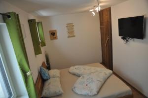 Habitación pequeña con cama con almohadas y TV. en Ferienwohnung Bärbel, en Sautens
