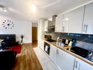 a kitchen with white cabinets and a clock on the wall at Captivating 2-Bed Apartment in Bedford in Bedford