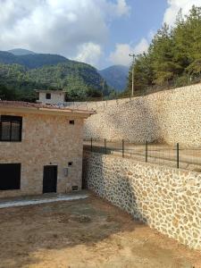una pared de piedra junto a un edificio con una valla en çamlıbel şelale villaları, en Alanya