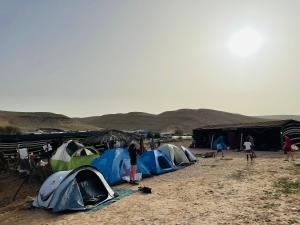 a group of tents in the desert with people standing around at חאן נחל חווה Han Nahal Hava in Mitzpe Ramon