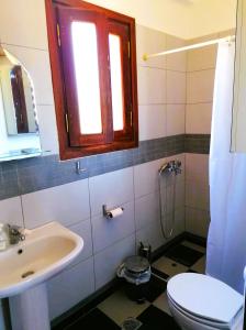 ein Bad mit einem Waschbecken, einem WC und einem Fenster in der Unterkunft Litani Villa in Raches