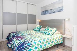 Un dormitorio con una cama con almohadas azules y verdes. en Los Alamos de Cotillo, en Cotillo