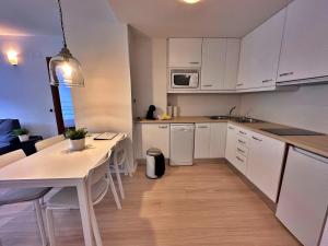 a kitchen with white cabinets and a white table at Tucamp 2.6 justo al lado del telecabina in Encamp