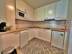 a kitchen with white cabinets and a tile floor at Tucamp 2.6 justo al lado del telecabina in Encamp
