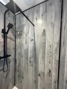 a shower in a bathroom with a wooden wall at Boutique Nights Willow in Eastbourne