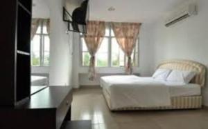 a bedroom with a bed and two windows at Melawati Ria Hotel in Kuala Selangor