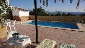a pool with a table and chairs next to a house at Gîte rural 100 % authentique (8 pers) avec piscine in Los Arenales