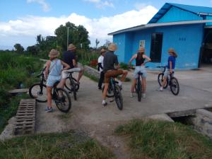 a group of people riding bikes in front of a blue building at Umah Desa in Banjarangkan