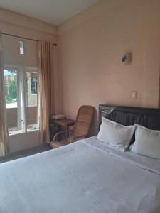 a bedroom with a bed and a chair and a window at RON'S Guest House Berastagi in Berastagi