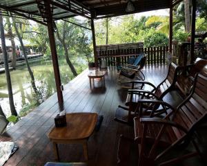 a porch with chairs and tables and a view of a river at Aple Homestay in Amphawa