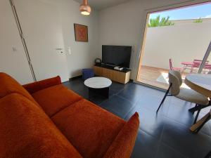 a living room with a couch and a television at Escapade aux dunes in Brétignolles-sur-Mer