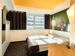 Schlafzimmer mit einem Bett, einem Schreibtisch und einem Fenster in der Unterkunft B&B Hotel Duisburg Hbf-Süd in Duisburg