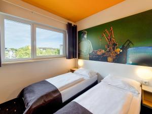 - une chambre avec 2 lits et une fenêtre dans l'établissement B&B Hotel Duisburg Hbf-Süd, à Duisbourg