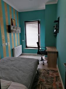 a bedroom with a bed and a desk and a window at Queency Apartament cu gradina și parcare gratuita in Cluj-Napoca