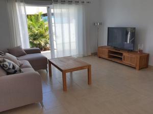 un soggiorno con TV, divano e tavolo di Casa Sandra, private saltwater pool and garden a Tacoronte