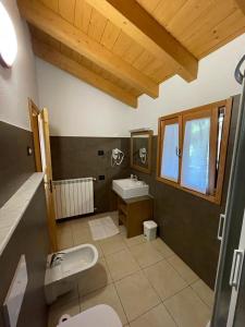 La salle de bains est pourvue d'un lavabo, de toilettes et d'une fenêtre. dans l'établissement Orobie Holiday Apartments, à Albosaggia