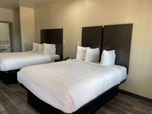 Habitación de hotel con 2 camas con sábanas blancas en Days Inn by Wyndham Dickinson TX, en Dickinson