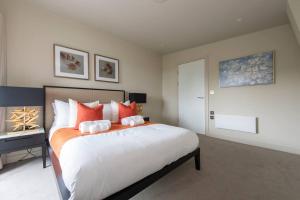una camera da letto con un grande letto con cuscini arancioni e bianchi di Chigwell 1BR + Study Escape a Chigwell