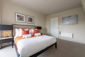 a bedroom with a large bed with orange and white pillows at Chigwell 1BR + Study Escape in Chigwell