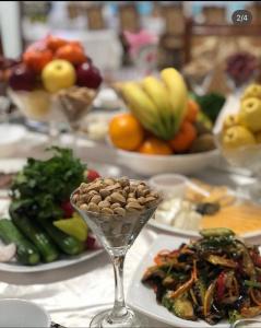 einen Tisch mit Teller mit Lebensmitteln und Schalen mit Früchten in der Unterkunft Shokhjakhon Parvoz in Xiva